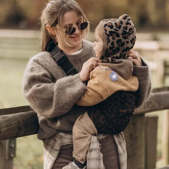 Maman au parc avec bebe dans porte bebe naissance