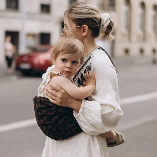Maman dans la rue avec bebe dans porte bebe naissance