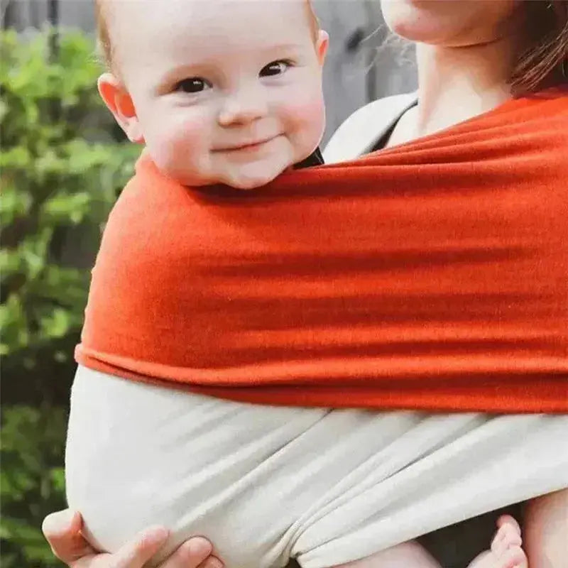 bebe sourrit dans echarpe de portage bebe