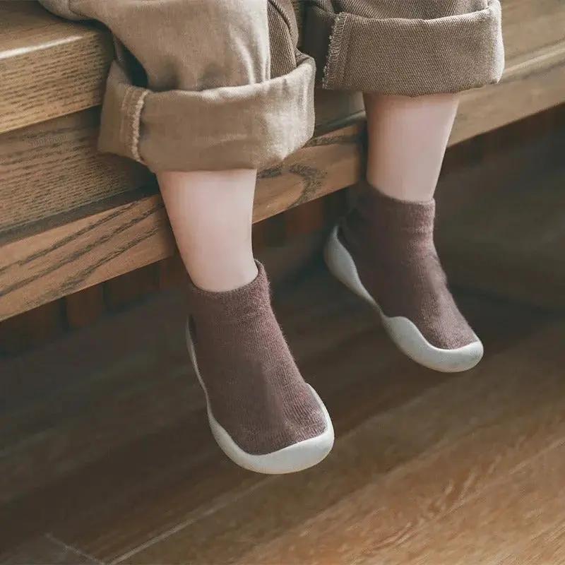 enfant assis avec premiere chaussure bebe au pied