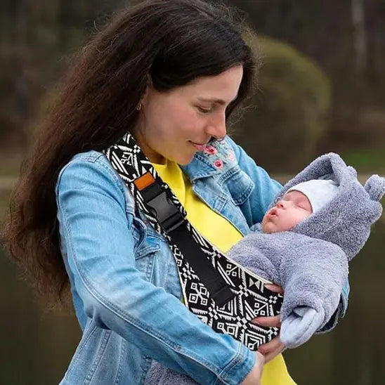 maman dehors avec bebe dans echarpe de portage sling