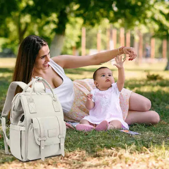 maman et bebe assise terre parc avec sac a langer