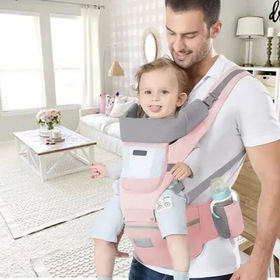 papa au salon sourit avec bebe dans porte bebe
