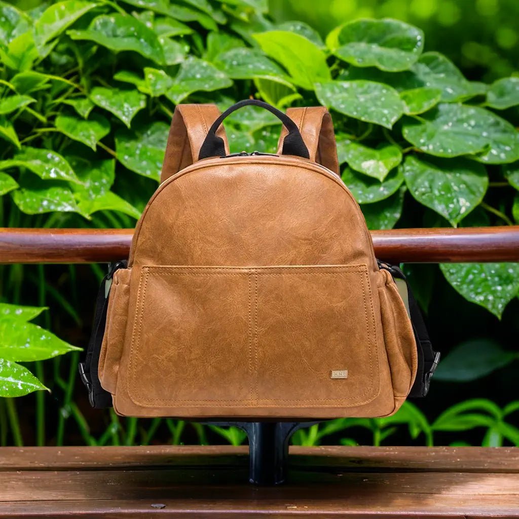 sac a langer marron sur un banc devant un jardin