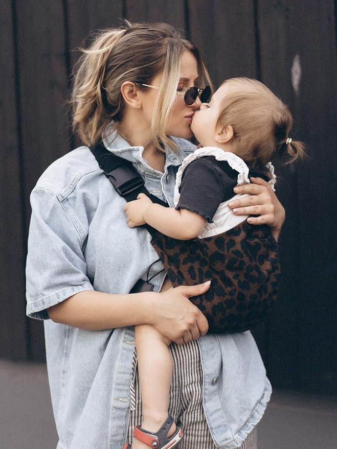 Maman embrasse fille dans porte bebe naissance