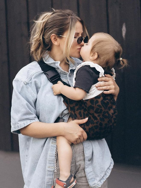 Maman embrasse fille dans porte bebe naissance