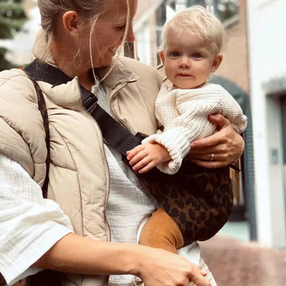 Maman regarde bebe dans porte bebe naissance