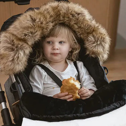 bebe dans chanceliere avec croissant en main