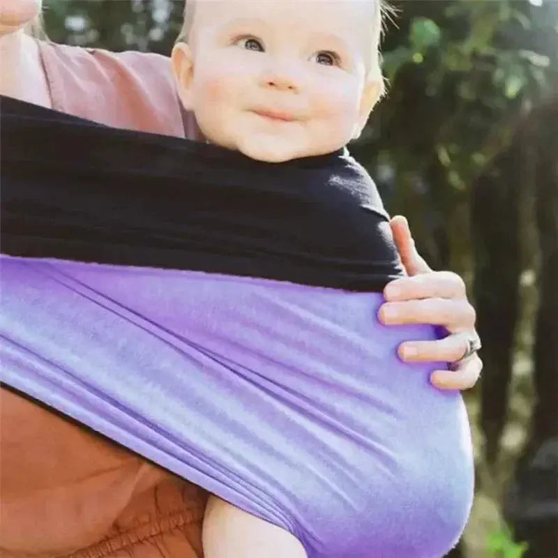 bebe sourrit dans echarpe de portage mauve