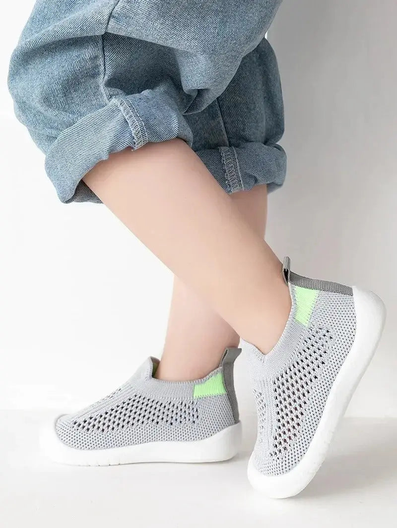 enfant debout pied croise avec chaussure bebe gris