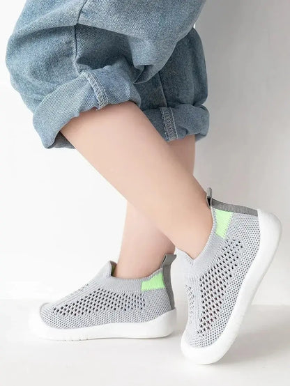 enfant debout pied croise avec chaussure bebe gris